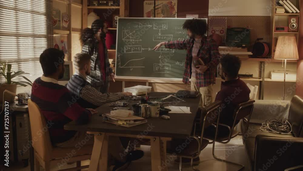 Multiethnic male programmers team discussing program scheme on ...