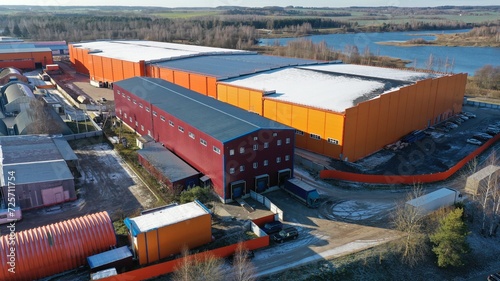 Buildings of warehouses storing finished products of a huge industrial plant. Warehouses made of steel structures, with flat snow-covered roofs, with ramps for unloading and loading goods from trucks