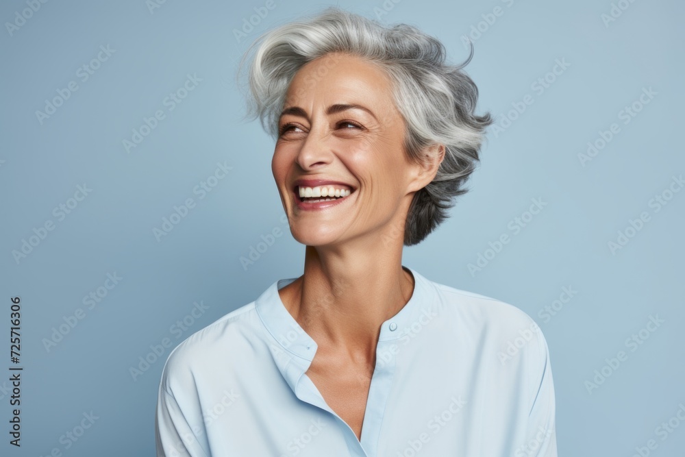 Cheerful mature woman with grey hair smiling and looking at camera.