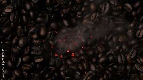 Close-up of dark roasted coffee beans. Smoke rises from the coffee beans. Fragrant coffee beans. A red heater can be seen from below.
