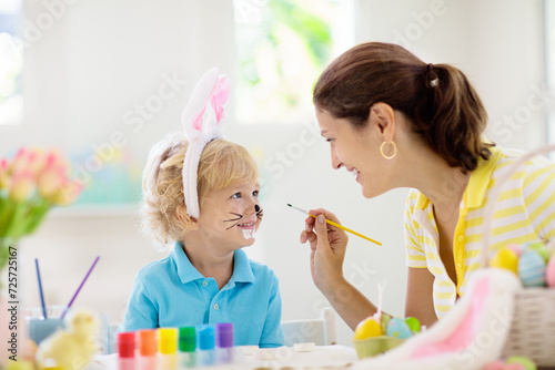 Mother and kids, family coloring Easter eggs.