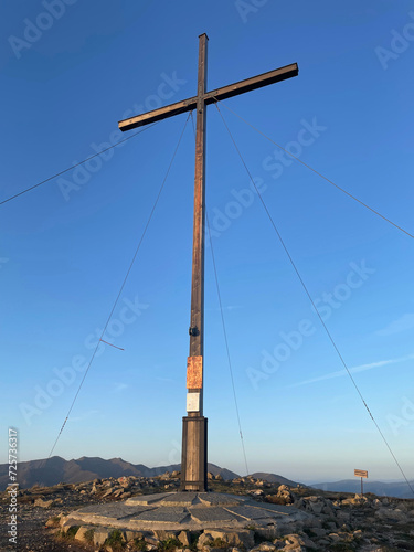 large summit cross marking the top of the mountain with a clear blue sky in the background