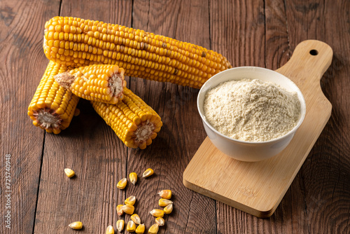 Fotografie Cornmeal in a cup and dry cobs on a wooden table.