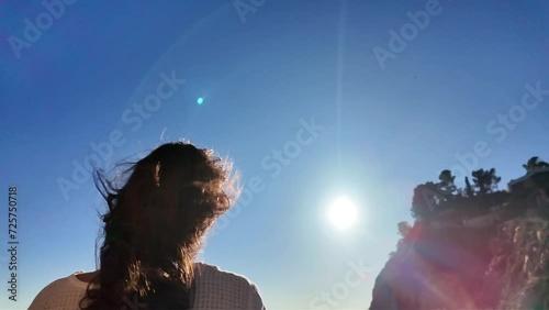 a relaxed young brunette girl with long hair on her back looking at the blue sky with lots of sunshine in slow motion