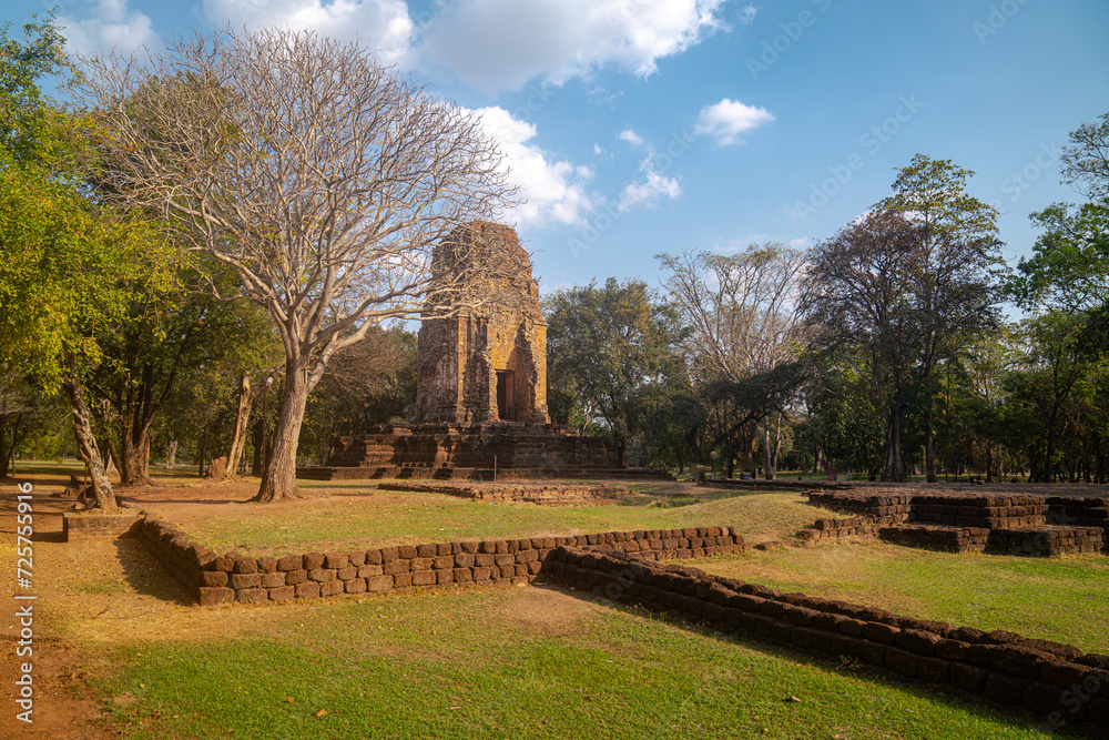 The ruins of an old castle built with laterite bricks of the ancient city of Si Thep..Ancient Angkor Temple Tower Amidst Park's Historic Stone Ruins and Towering Trees .in Si Thep Historical Park.