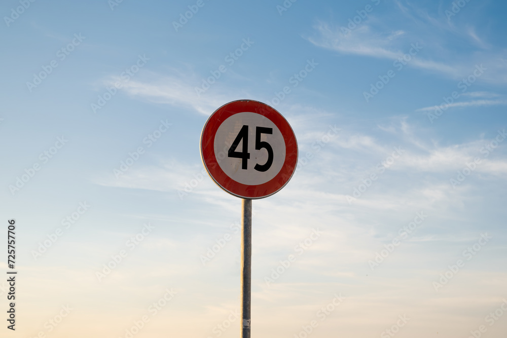 45 miles km maximum speed limit traffic sign isolated with sunset sky