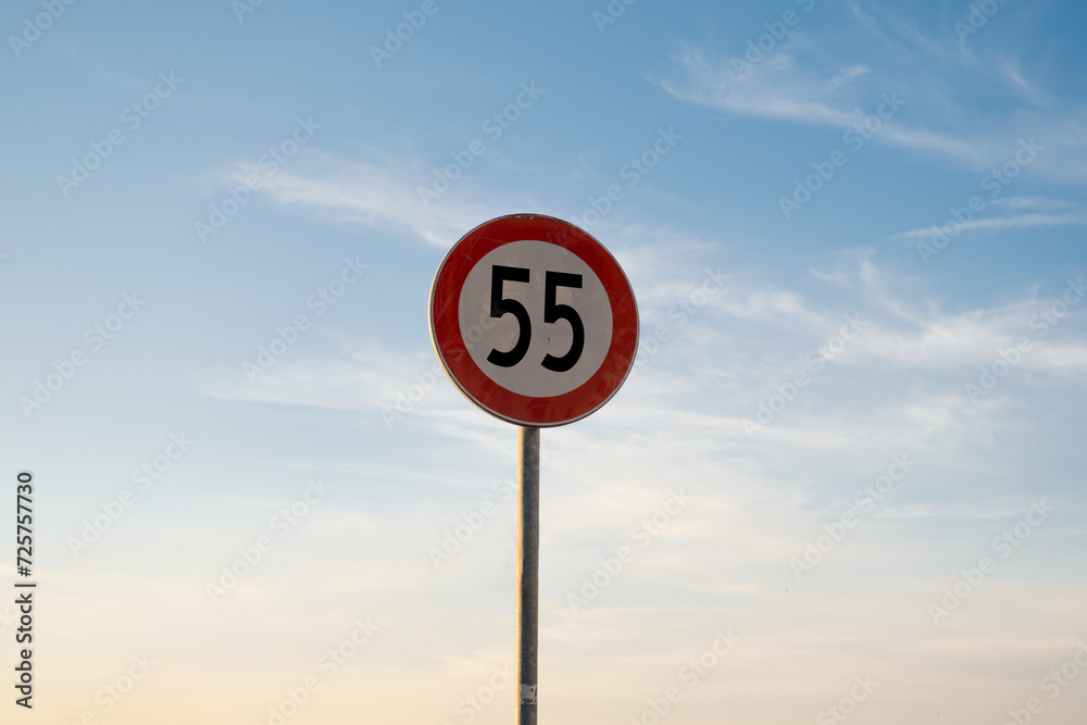 55 miles km maximum speed limit traffic sign isolated with sunset sky