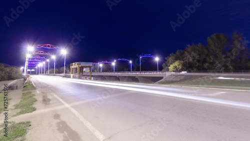 Timelapse Hyperlapse of Traffic on a Bridge in Uralsk. Illuminated Streets Cast a Vibrant Glow, Capturing the City's Nocturnal Pulse in Kazakhstan photo