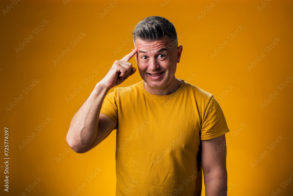 Smiling man touching head with finger showing great idea gesture.
