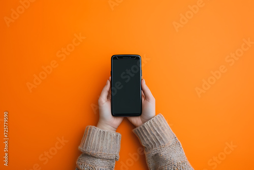 person holding a smartphone on an orange background i photo