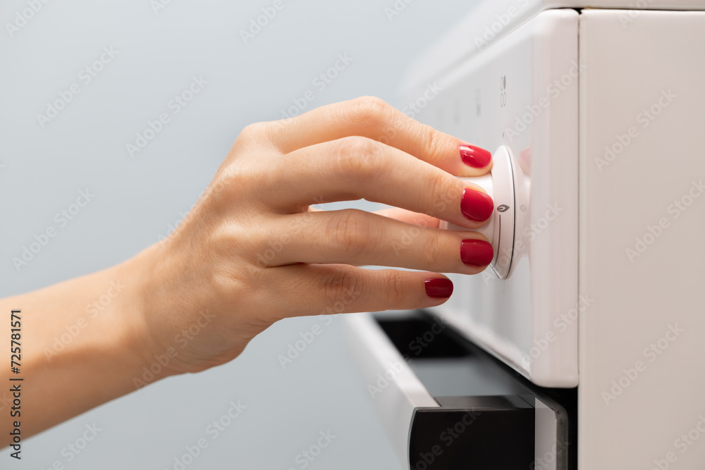 Naklejka premium a woman's hand rotates the selector on a gas stove