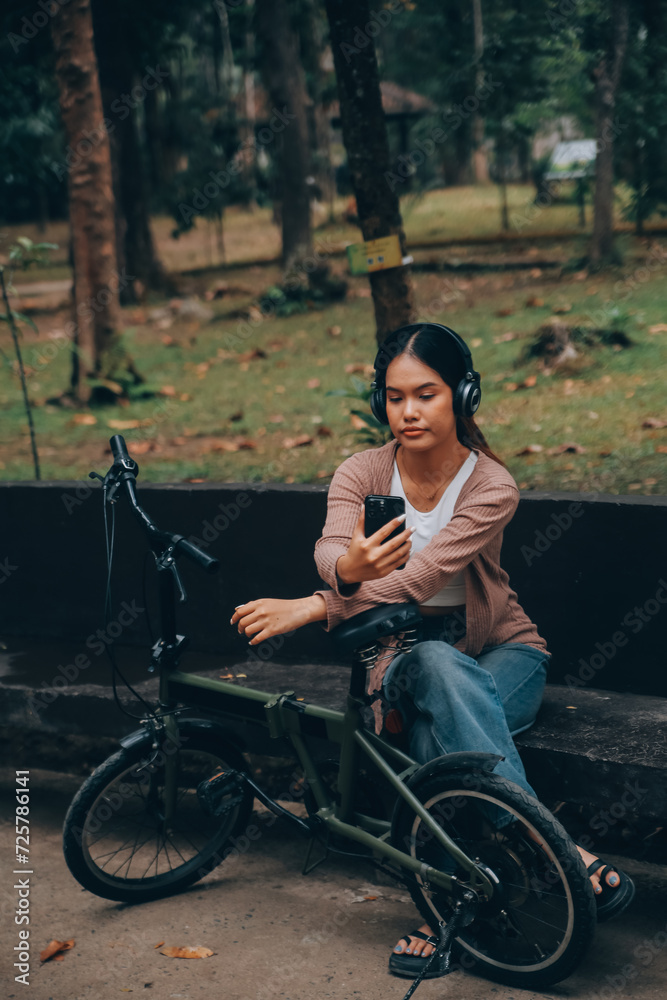 Happy young Asian woman while riding a bicycle in a city park. She smiled using the bicycle of transportation. Environmentally friendly concept. Happy young Asian woman while riding a bicycle in a city park. She smiled using the bicycle of transportation. Environmentally friendly concept.