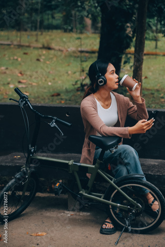 Happy young Asian woman while riding a bicycle in a city park. She smiled using the bicycle of transportation. Environmentally friendly concept. © ARMMY PICCA