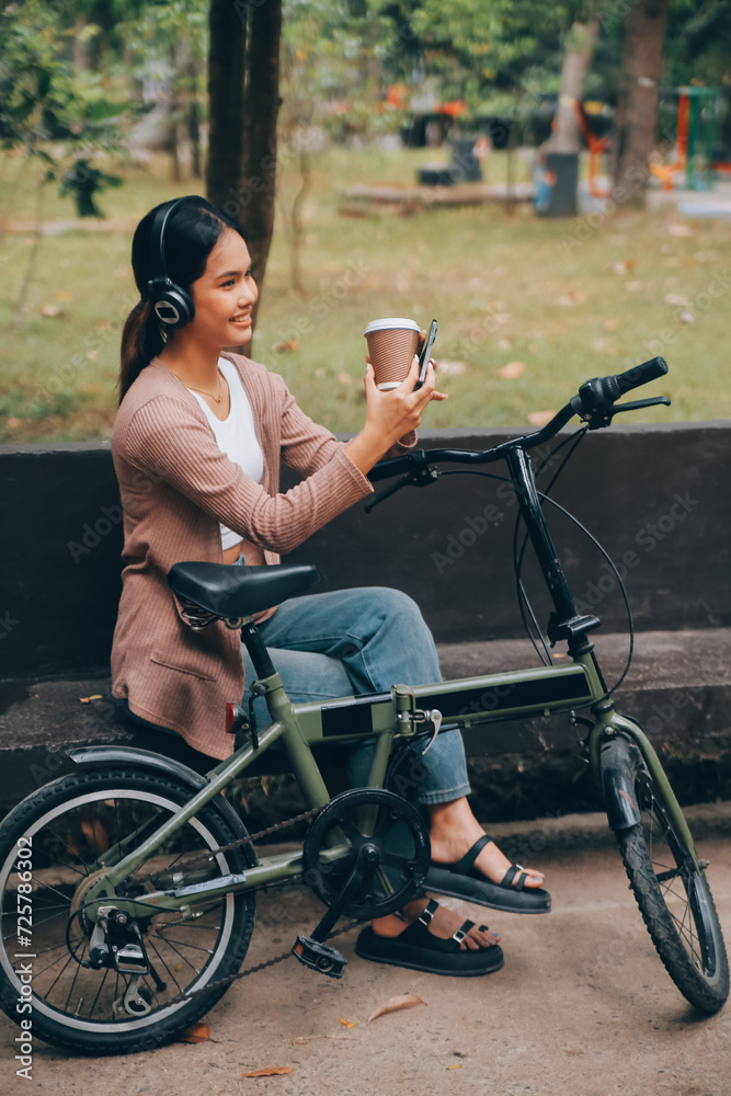 Obraz premium Happy young Asian woman while riding a bicycle in a city park. She smiled using the bicycle of transportation. Environmentally friendly concept.