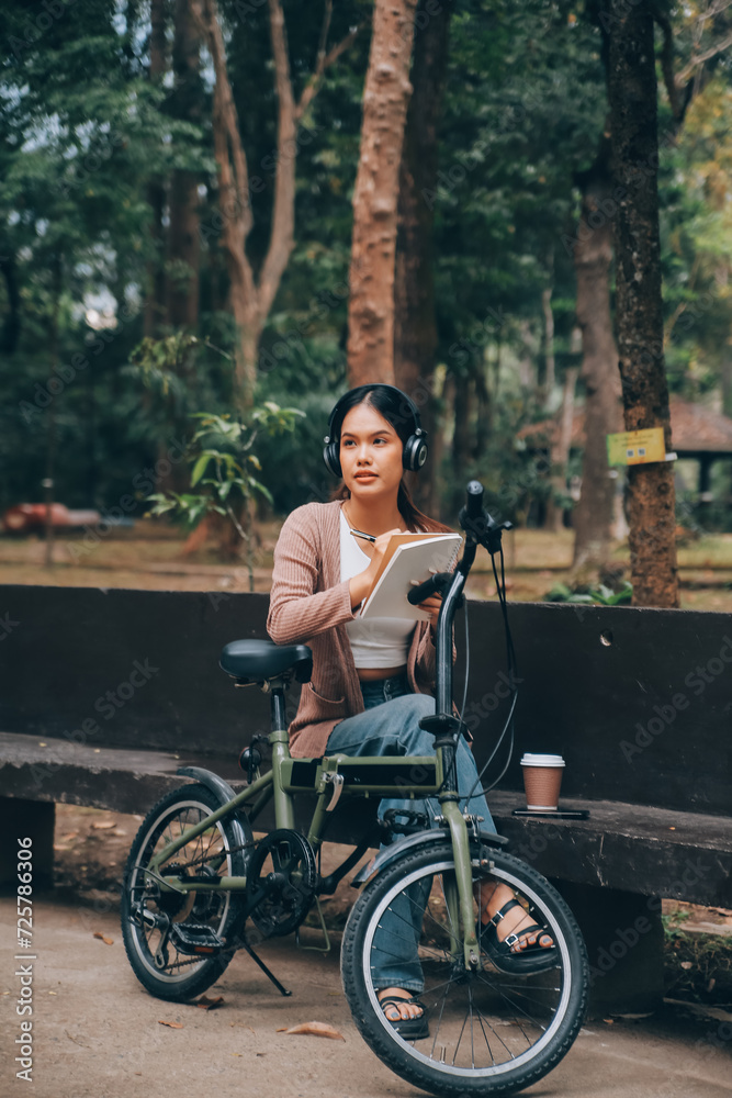 Happy young Asian woman while riding a bicycle in a city park. She smiled using the bicycle of transportation. Environmentally friendly concept. Happy young Asian woman while riding a bicycle in a city park. She smiled using the bicycle of transportation. Environmentally friendly concept.