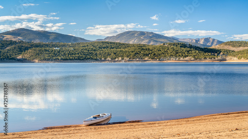 expedition canoe on a sandy beach of Carter Lake in northern Colorado, warm winter afternoon