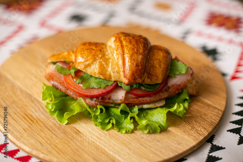 Croissant filled with bacon and tomatoes on a wooden background
