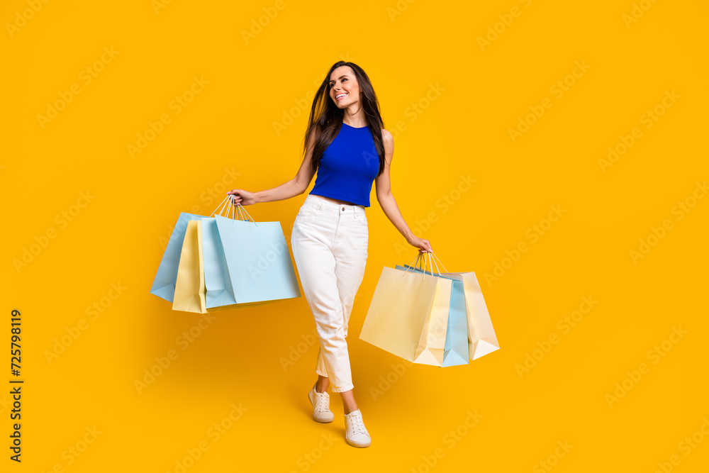 Full length photo of dreamy sweet woman wear blue top holding bargains looking empty space isolated yellow color background Full length photo of dreamy sweet woman wear blue top holding bargains looking empty space isolated yellow color background