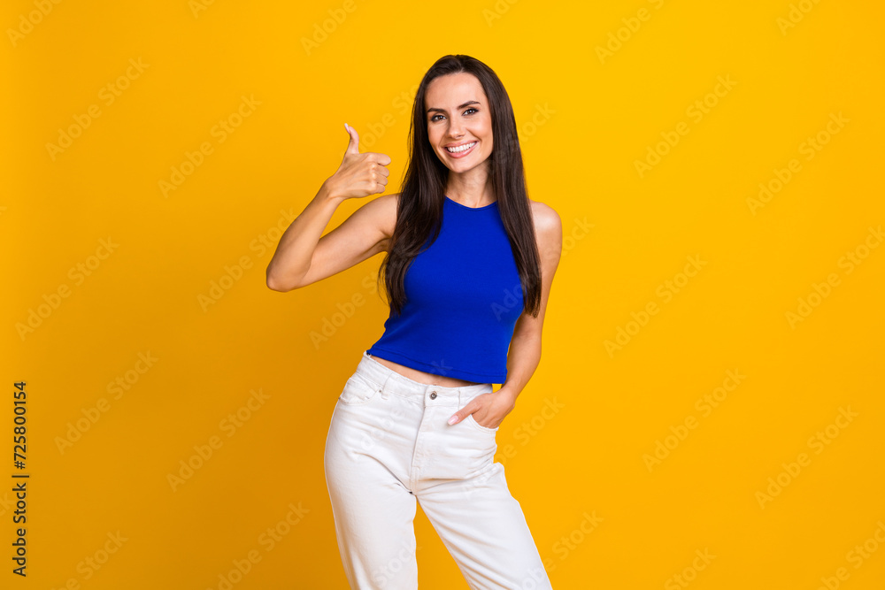 Photo of charming adorable woman wear blue top showing thumb up smiling isolated yellow color background Photo of charming adorable woman wear blue top showing thumb up smiling isolated yellow color background