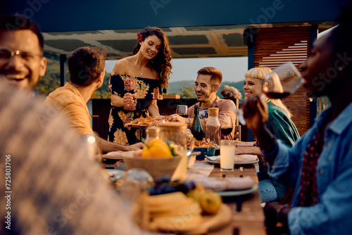 Happy woman serving food to her friends at dining table on patio.