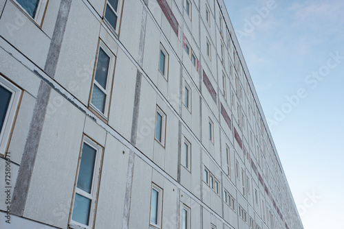facade of a old sad depressing worn apartment complex, going towards the horizon.