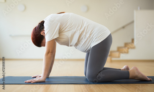 Pregnant woman is engaged in yoga. Cat Pose or Marjariasana photo