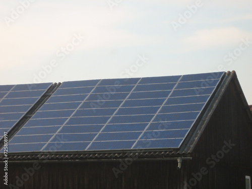Solar panels are installed on the roof of the barn to generate electricity against the background of the sky