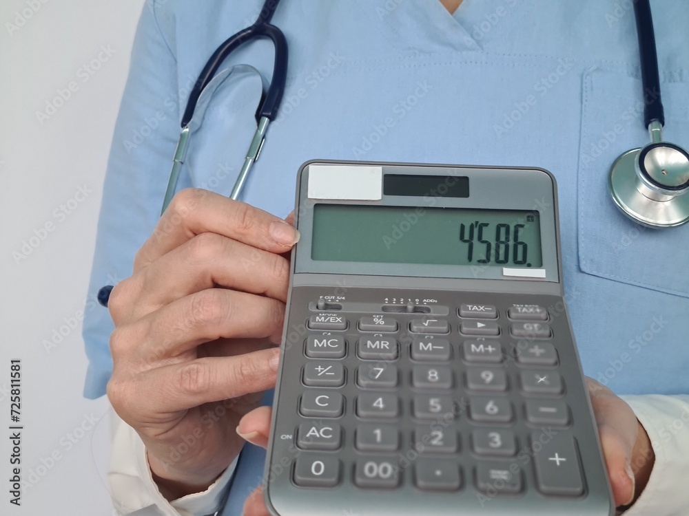 A doctor in scrubs is holding a calculator. Isolated on a white background. A doctor in scrubs is holding a calculator. Isolated on a white background.