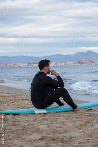 surfer sitting on surfboard on the beach