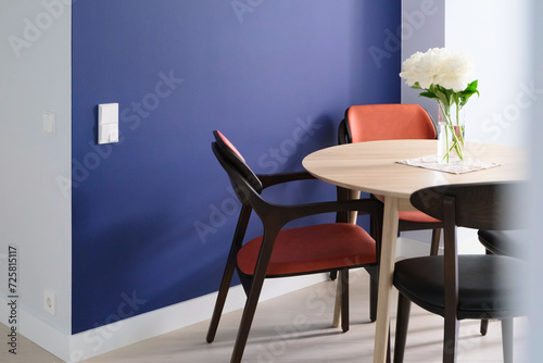 Fototapeta Naklejka Na Ścianę i Meble -  wooden table with peony flowers and chairs near colorful wall in modern empty dining room