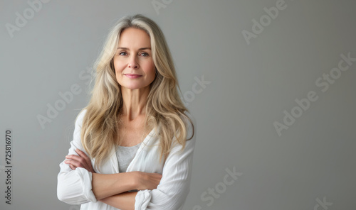 Smiling confident stylish 50s middle aged woman isolated on grey. Older businesswoman, lady executive business leader, manager or entrepreneur looking at camera arms crossed, portrait.