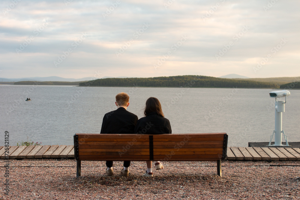 A man and a woman are sitting on a bench on the sea embankment. Rest