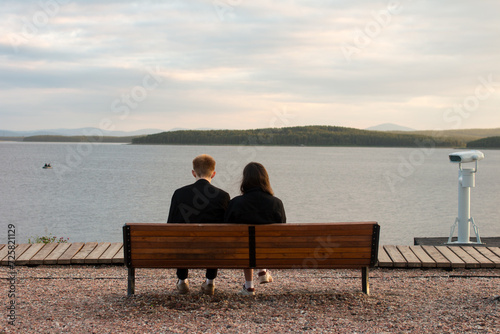 A man and a woman are sitting on a bench on the sea embankment. Rest
