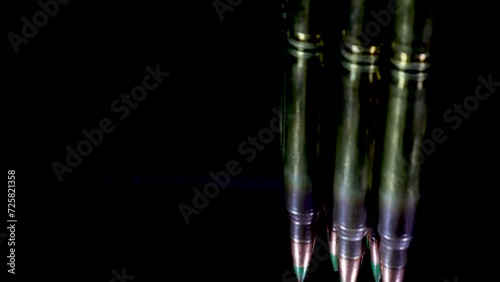 Rifle bullets rotate and cast their reflection on the glass table with a black background and cinematic look photo