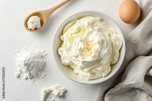 Top down view of a white kitchen table with a bowl of frothy egg whites