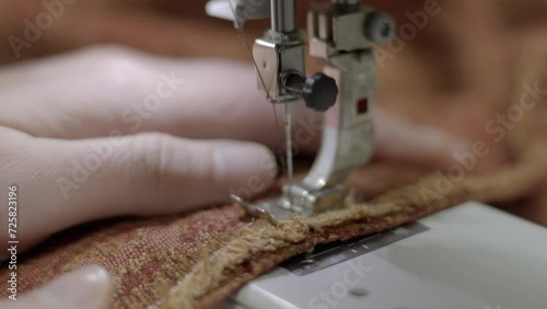 This video shows a close up view of red upholstery fabric being sewn on a sewing machine.  photo