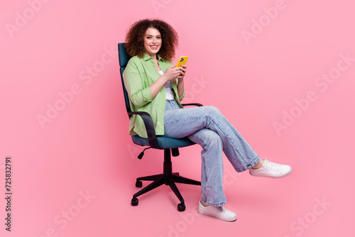 Photo portrait of pretty young girl sit armchair hold device wear trendy green outfit isolated on pink color background