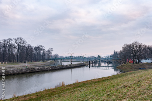 Metalowy most nad rzeką przy pochmurnym niebie © FIOMI