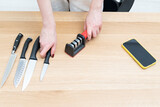 Close-up of woman sharpening knife with special knife sharpener at home	