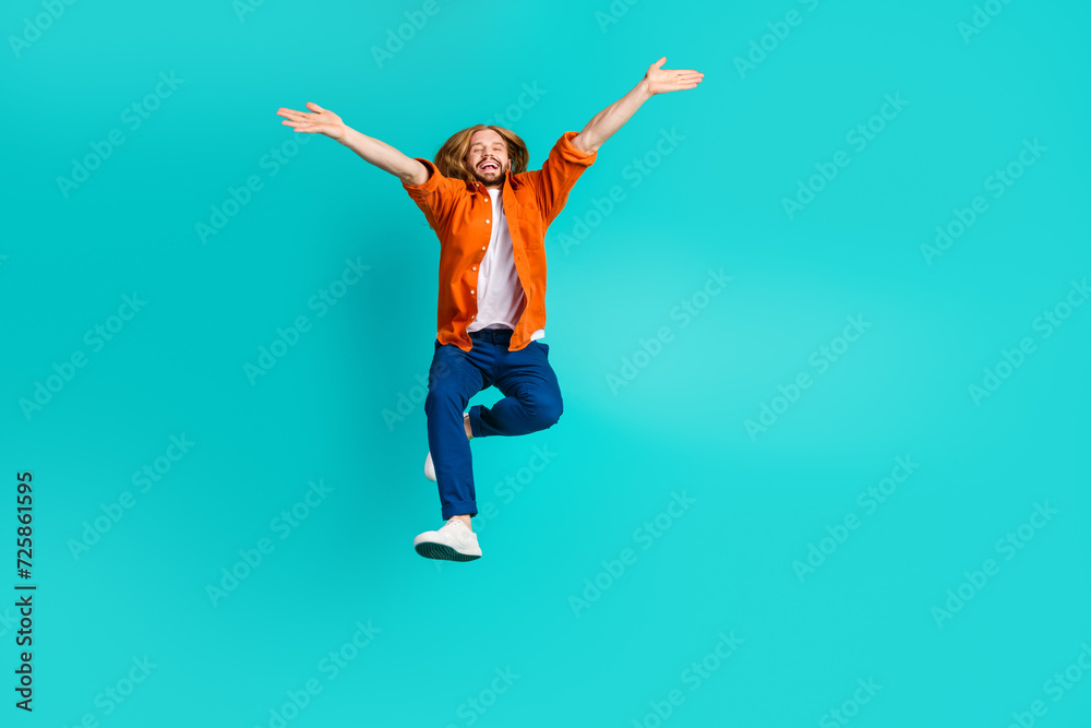Full length photo of optimistic man dressed orange shirt flying hands up demonstrate big season sale isolated on teal color background Full length photo of optimistic man dressed orange shirt flying hands up demonstrate big season sale isolated on teal color background