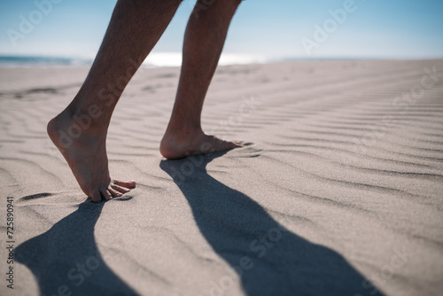 Men's bare feet on the sand. Close-up of the legs.