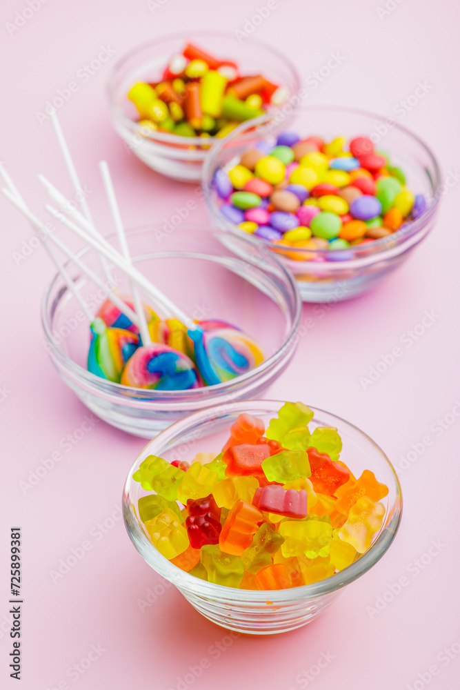 Colorful sweet jelly candies in bowl on pink background.