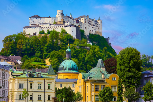 Salzburg, Austria. White Fortress medieval castle at cliff under the old town. Famous landmark with blue summer sky and green trees. Beautiful european architecture.