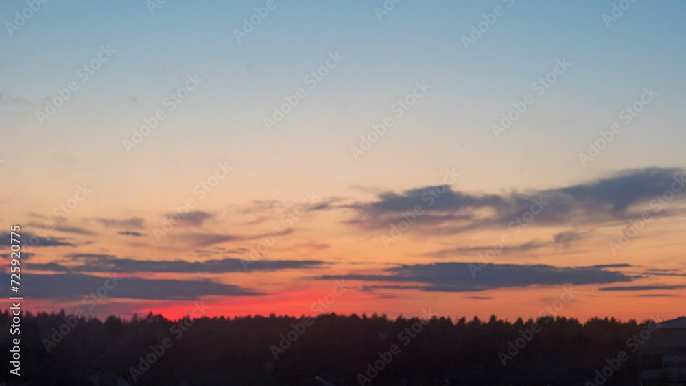 Sunset sky and sun through the clouds over. Golden sunset with blue colors.
