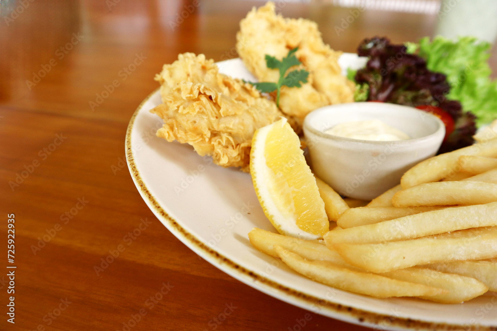 Traditional british fish and chips with tartar sauce, lemon slice and vegetable