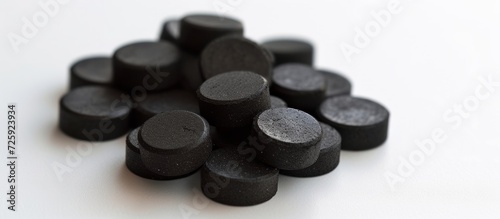 Activated carbon tablets in a round shape, black in color, placed on a white background.