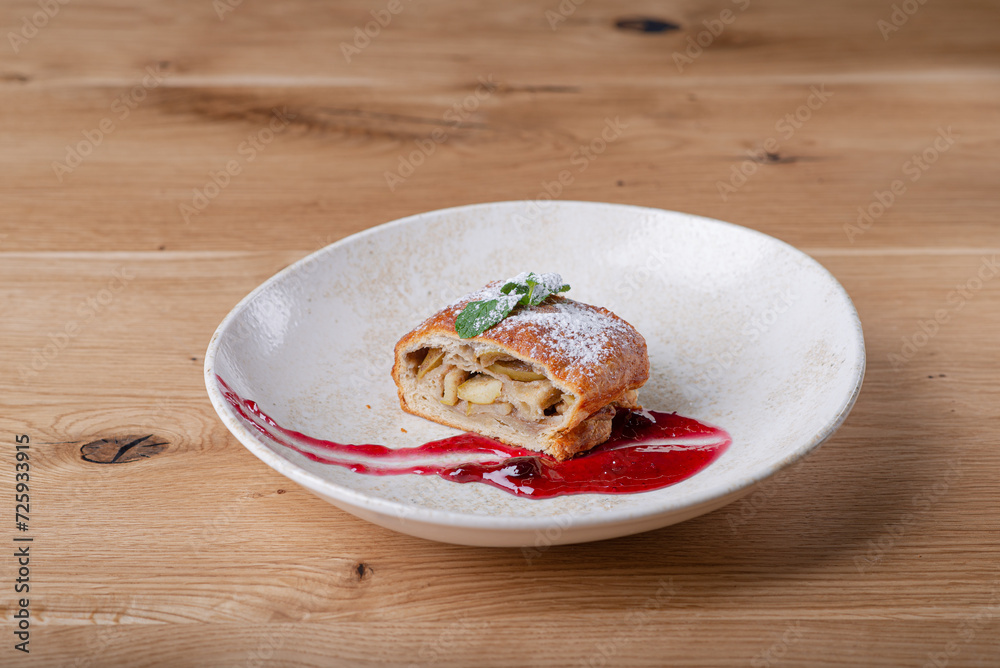 Cut apple strudel with berry sauce