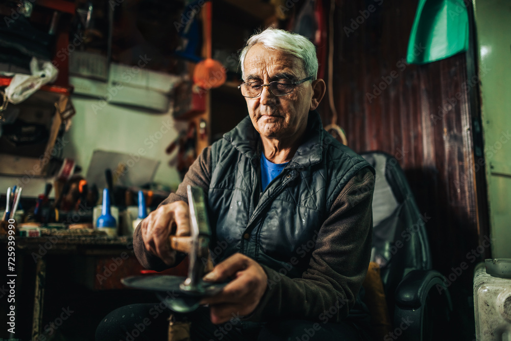Obraz premium Portrait of a senior cobbler at his shop working with shoes.