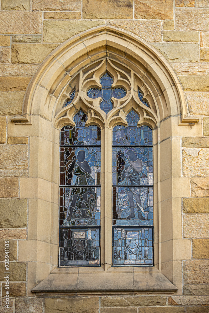 Santa Barbara, CA, USA - November 30, 2023: Trinity Episcopal Church, closeup of stained glass window set in sculpted stone frame on north side wall