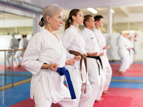 Adult people practicing taekwondo and warming up for training while standing barefoot
